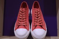 Coral canvas sneakers with white toe caps on a violet shelf — photo by Efrem Efre on Pexels