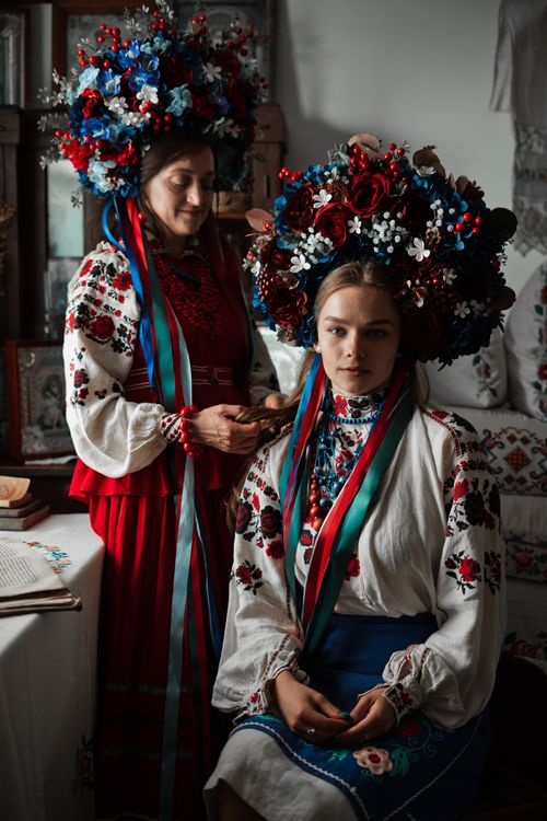Free Women in vibrant Ukrainian costumes with large floral headdresses captured indoors. Stock Photo
