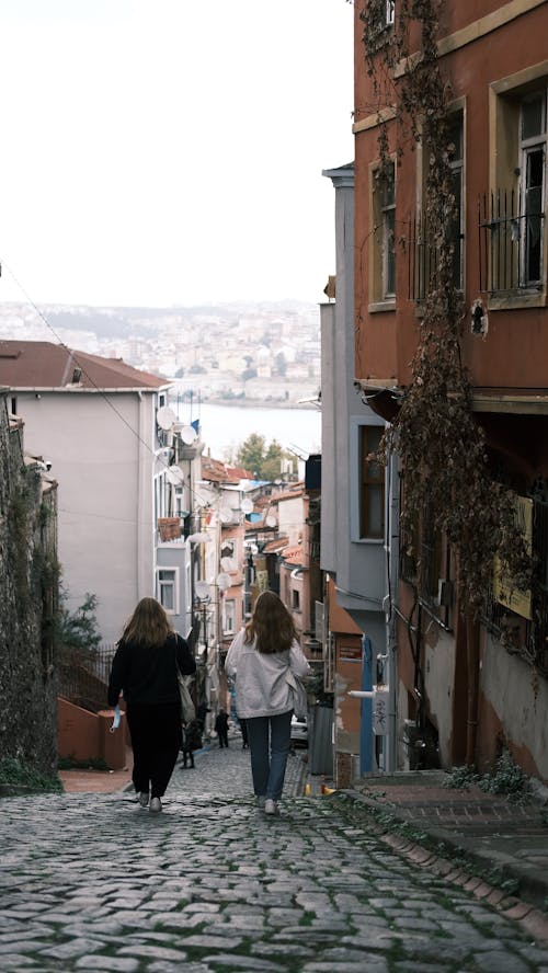 Back View of Women Walking on a Narrow Street 