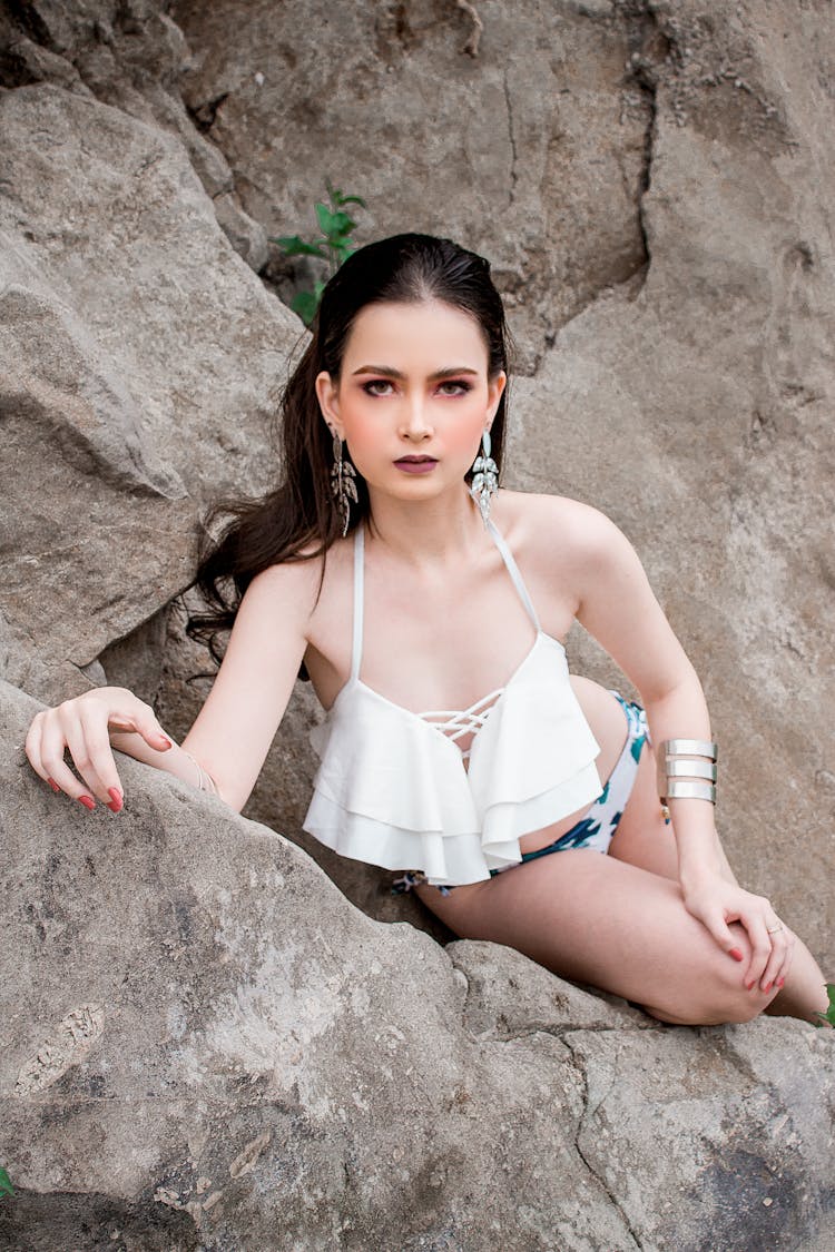 Woman In White Bikini Sitting On Rock