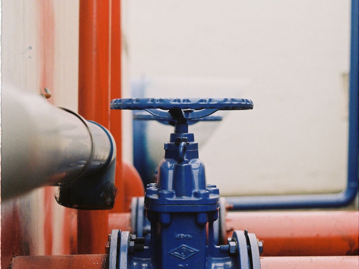 Close-up of a blue gate valve on red pipes.