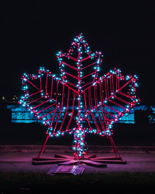 Free Brightly lit maple leaf decoration in vibrant colors against night sky, symbolizing Canada. Stock Photo