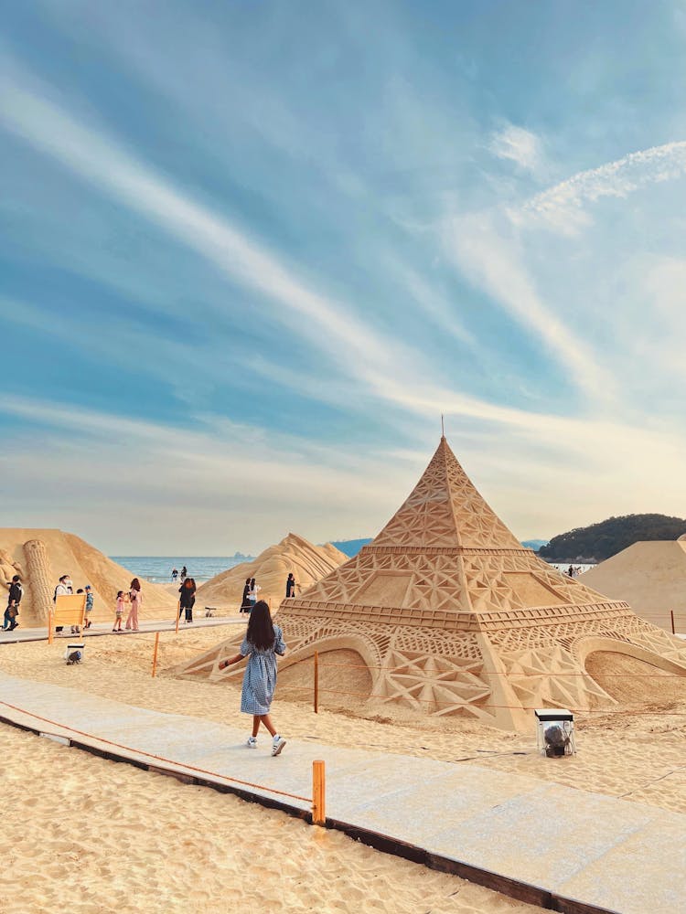 People Walking On Pathways Near Sand Sculptures