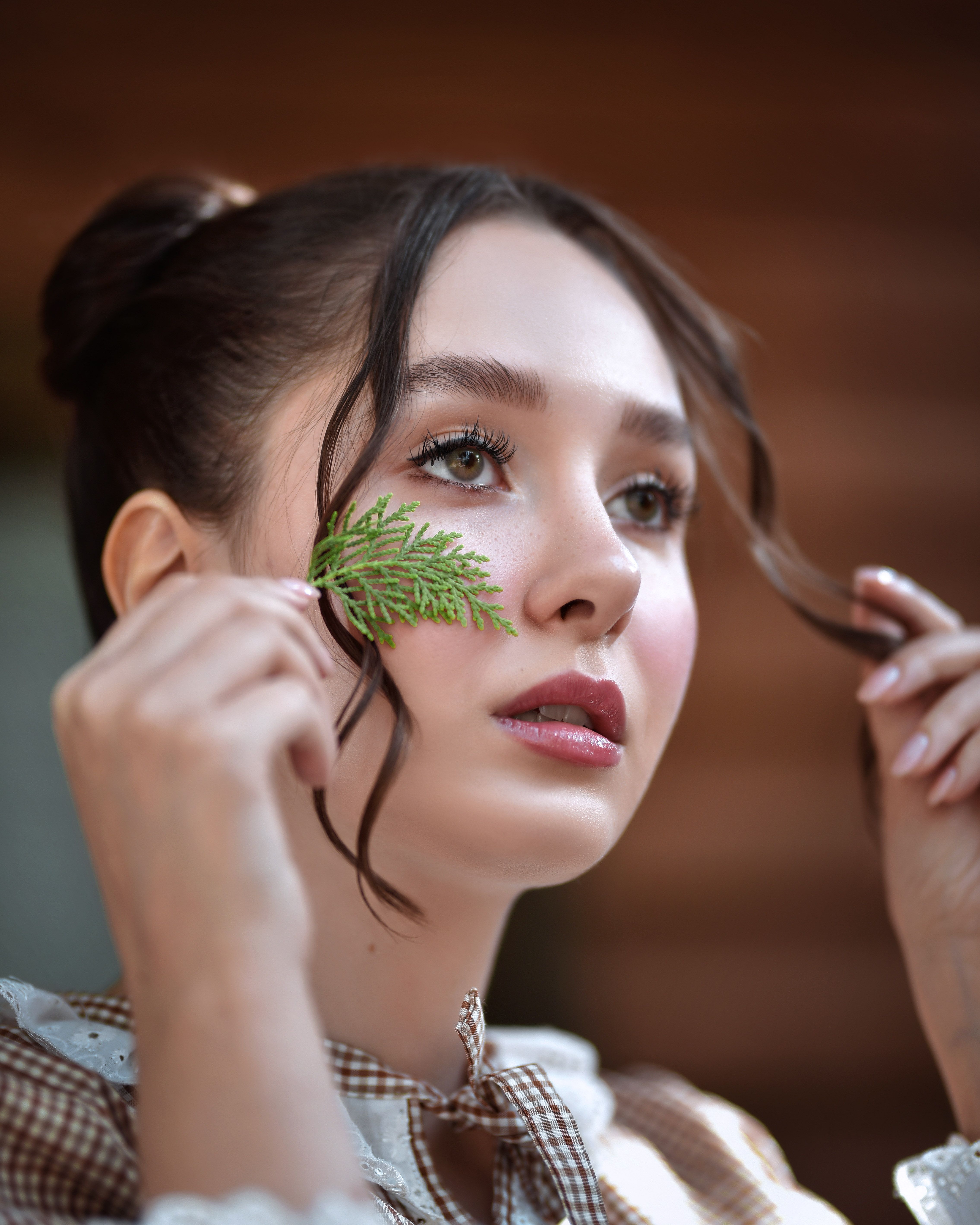 A serene portrait of a woman holding a thuja leaf, highlighting natural beauty and tranquility.