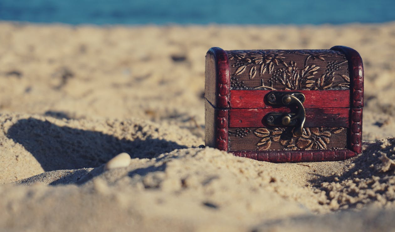 Free Red and Black Wooden Chest on White Sand Stock Photo