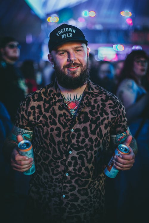 Photo of a Man with a Cap Holding Cans