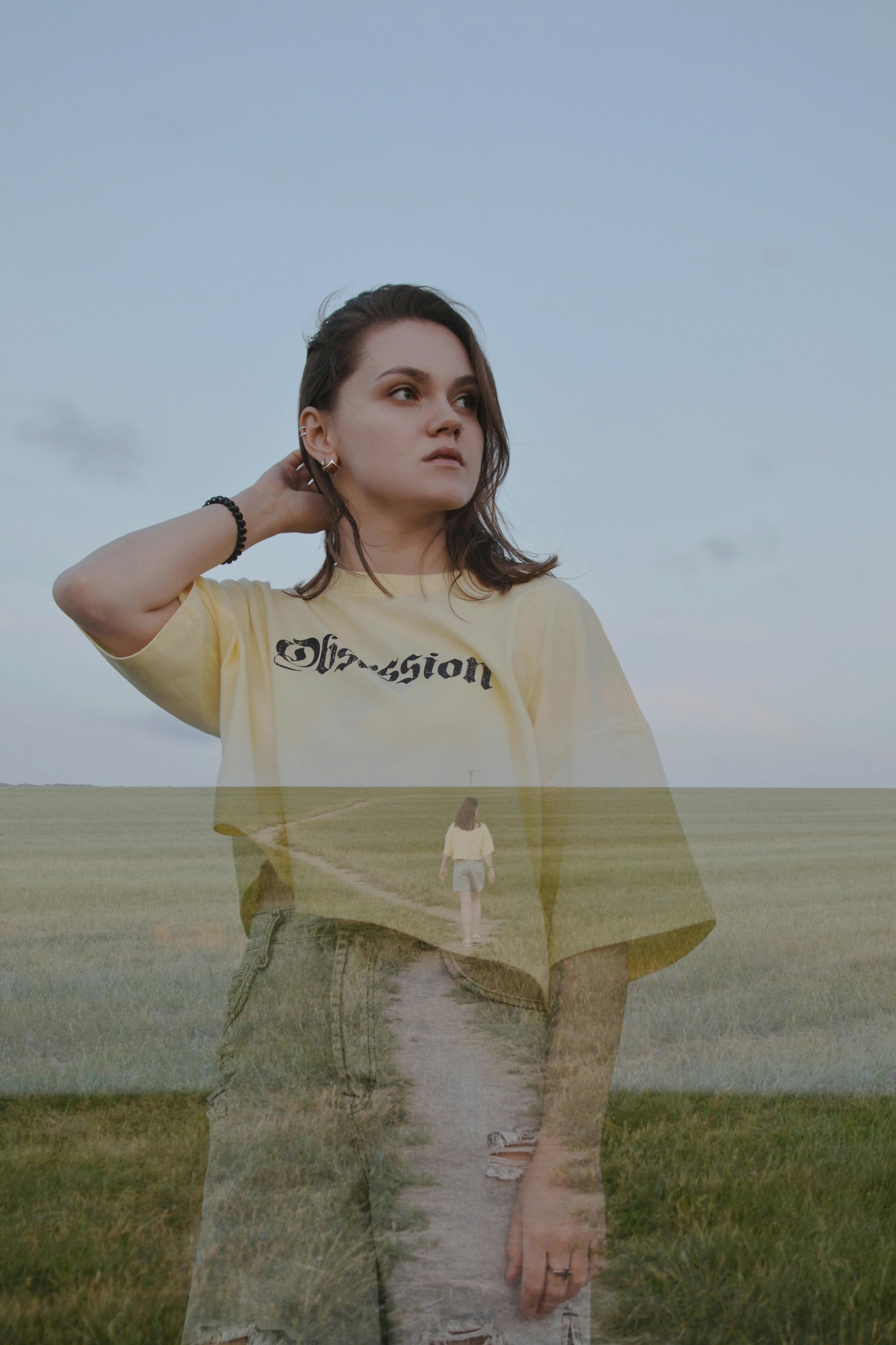 Artistic double exposure of a woman in a yellow shirt with a countryside setting.