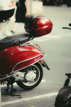 Close-up of a vibrant red scooter parked on an asphalt road in the city.