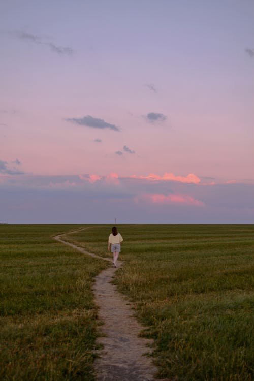 Woman Walking on Meadow at Dusk