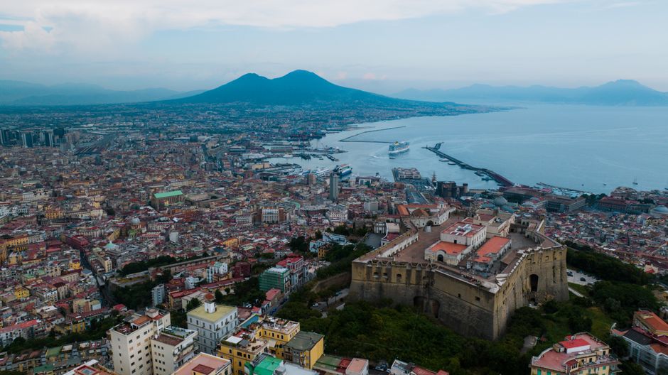 A stunning aerial view of Naples featuring the Castel Sant'Elmo and Mount Vesuvius.