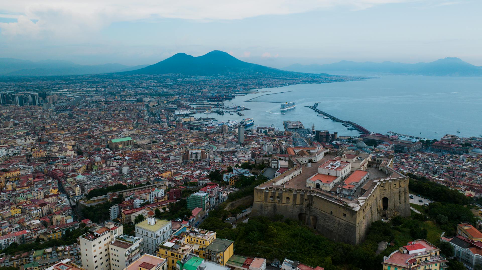 A stunning aerial view of Naples featuring the Castel Sant'Elmo and Mount Vesuvius.