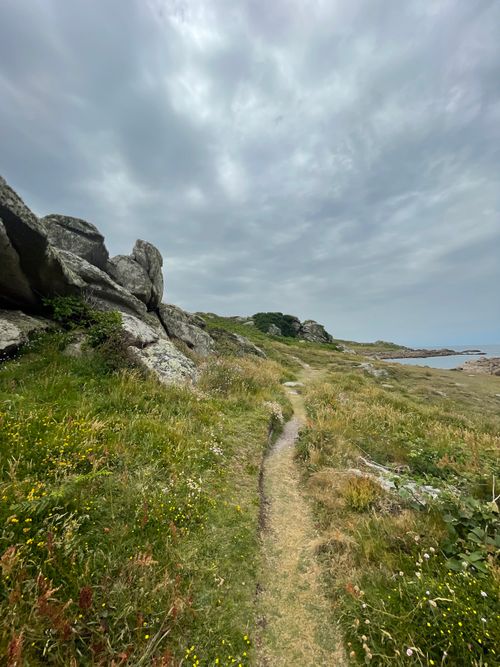 Free Explore a serene dirt path amid rocky landscapes and vibrant grass along England's coastline. Stock Photo