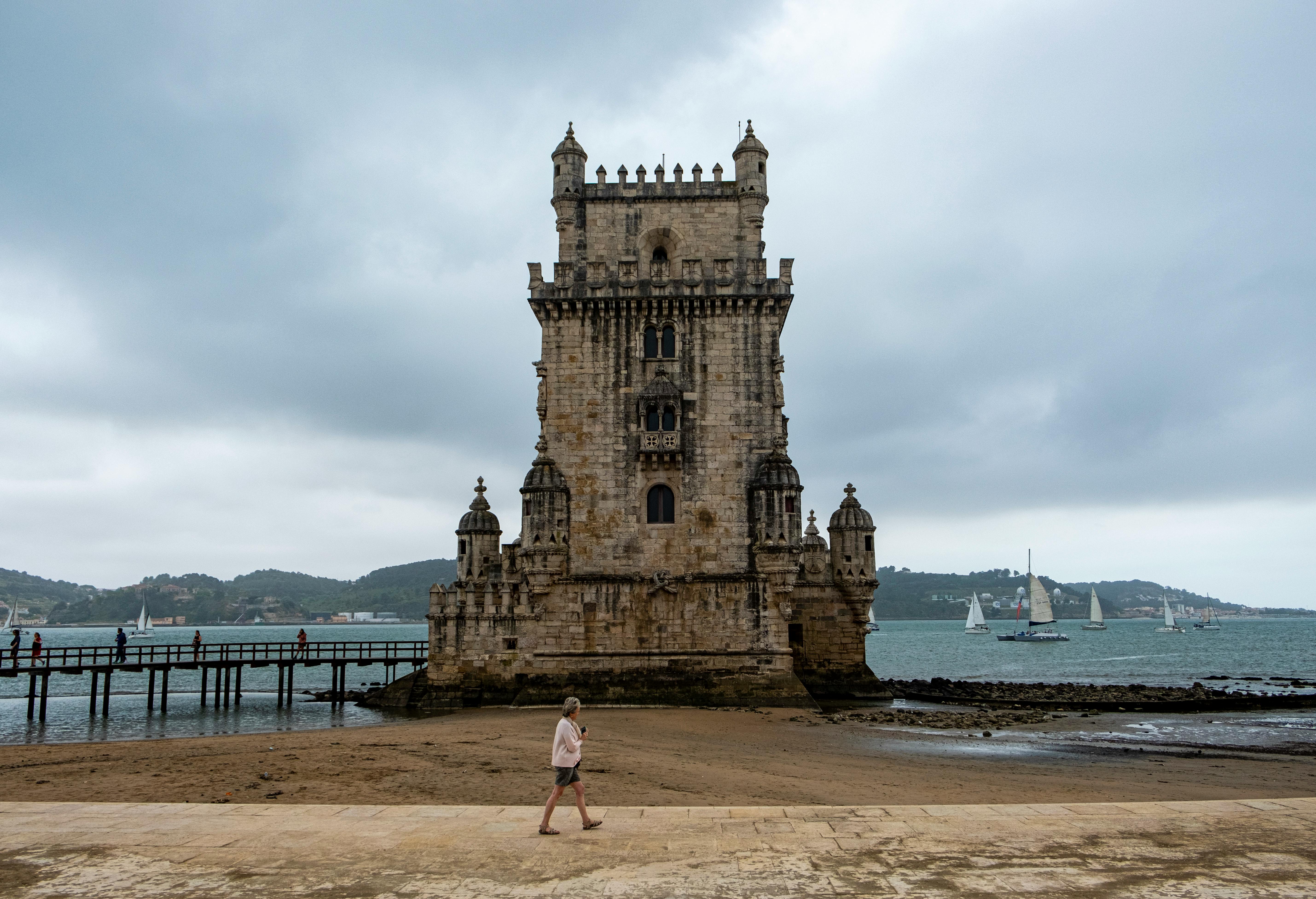 A Woman Walking Near the Brown Concrete Building · Free Stock Photo