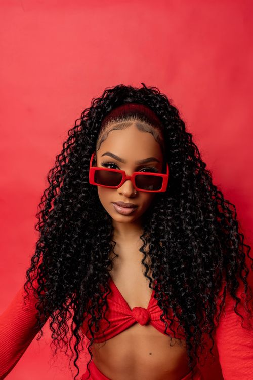 Free A fashionable woman poses with sunglasses, styled in bright red attire. Stock Photo