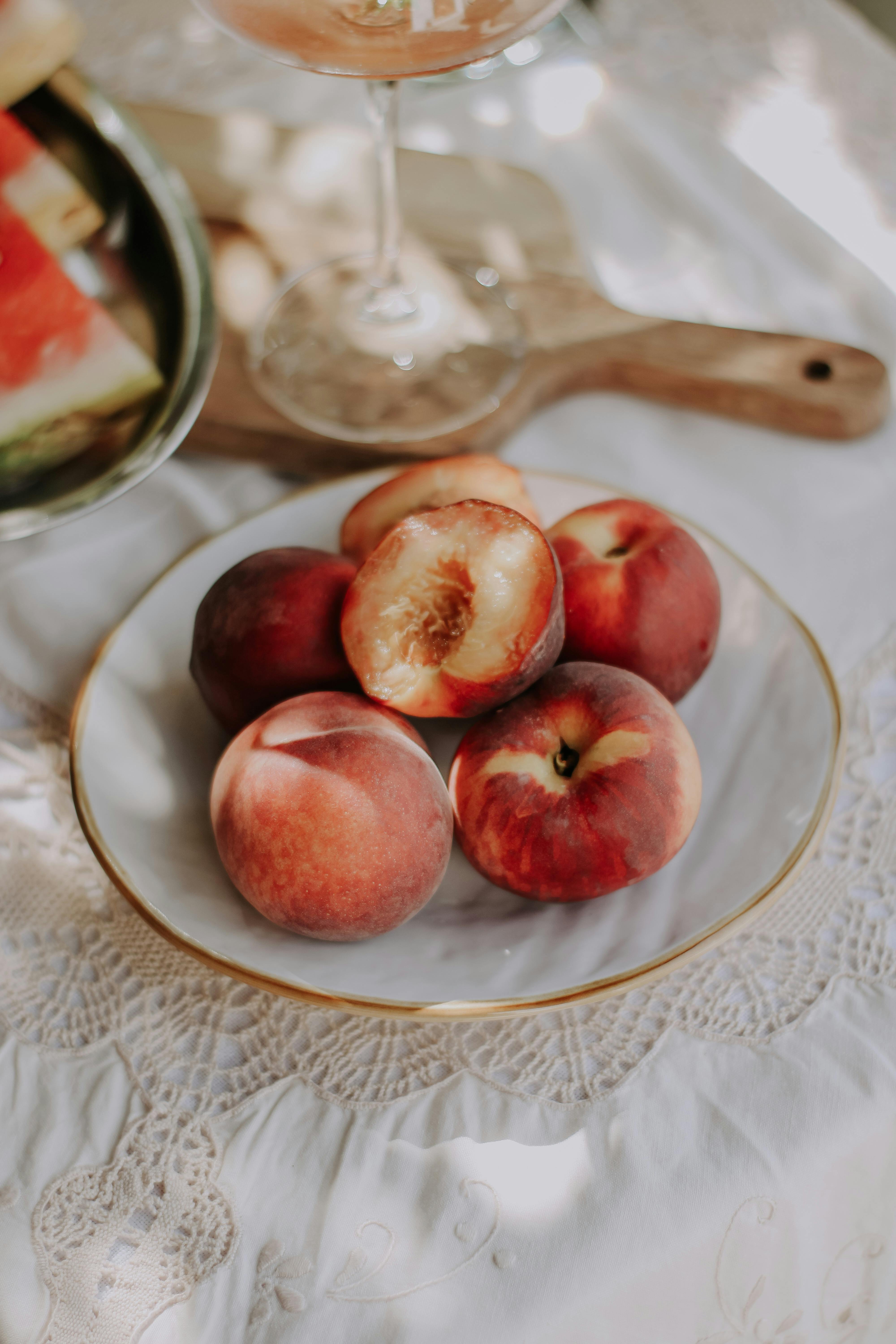 A plate of ripe peaches on a lace tablecloth, capturing the essence of a summer gathering.