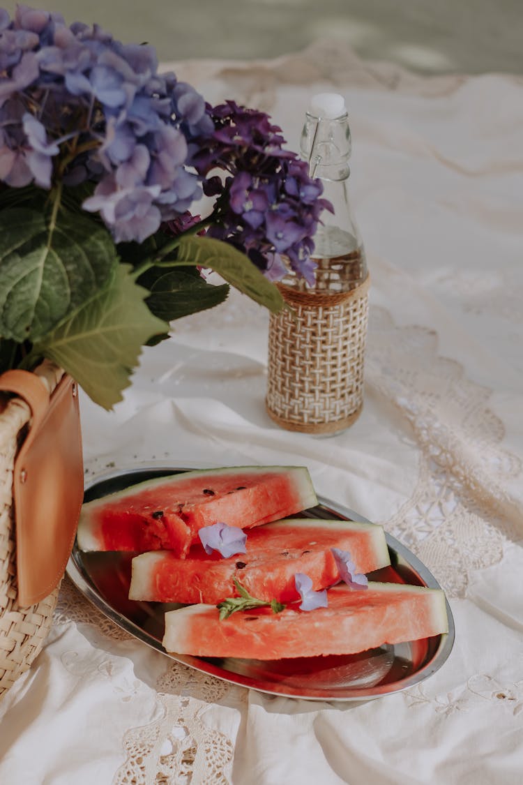 Slices Of Watermelon And Lilac Flower On Table