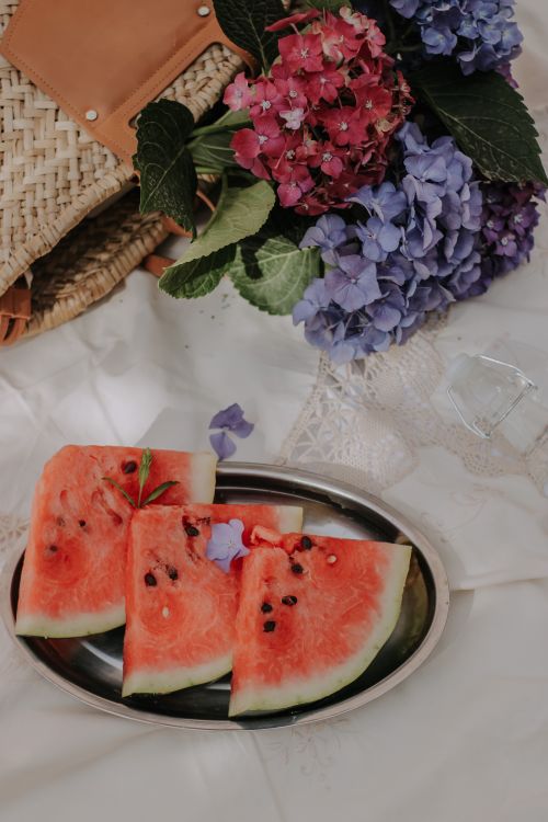 Free Slices of watermelon on a tray with vibrant hydrangea flowers, perfect for a summer picnic. Stock Photo