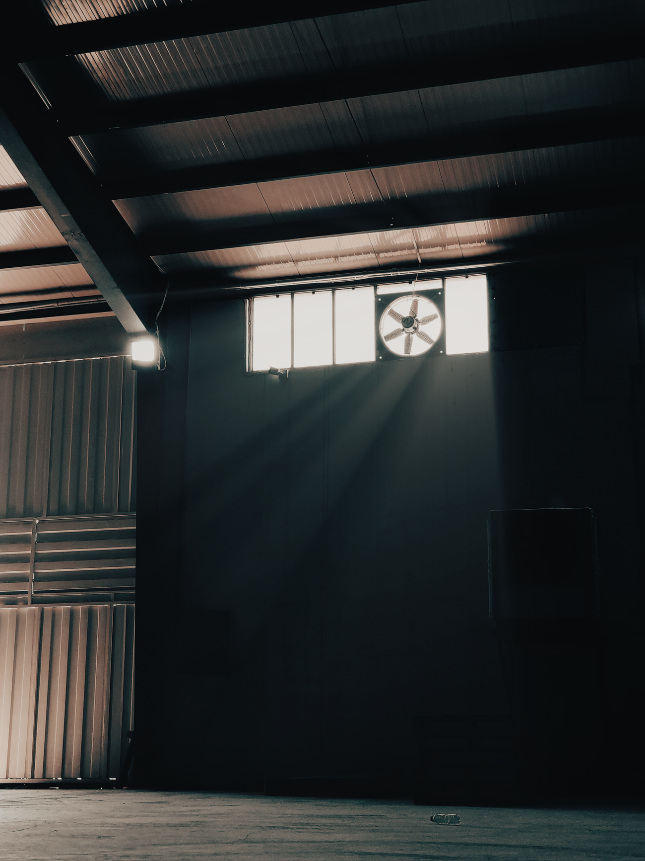 Illustrative warehouse exhaust fan in a large industrial interior.