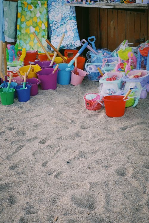 Free A vibrant collection of beach toys and buckets on a sandy beach, perfect for summer fun. Stock Photo
