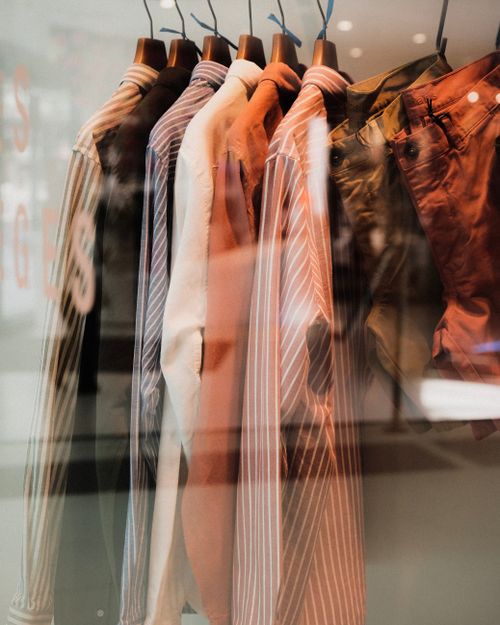 Free Fashionable clothing on hangers displayed behind a glass panel in a store. Stock Photo