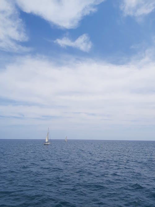 A Boat on the Sea Under the White Clouds and Blue Sky