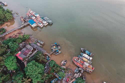 Free Aerial shot of fishing boats docked at a colorful village by the water's edge. Stock Photo