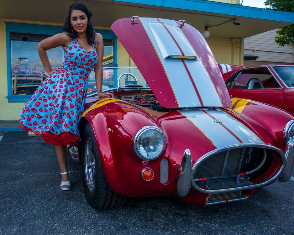 Woman in Blue and Red Dress Standing beside a Red Car · Free Stock Photo