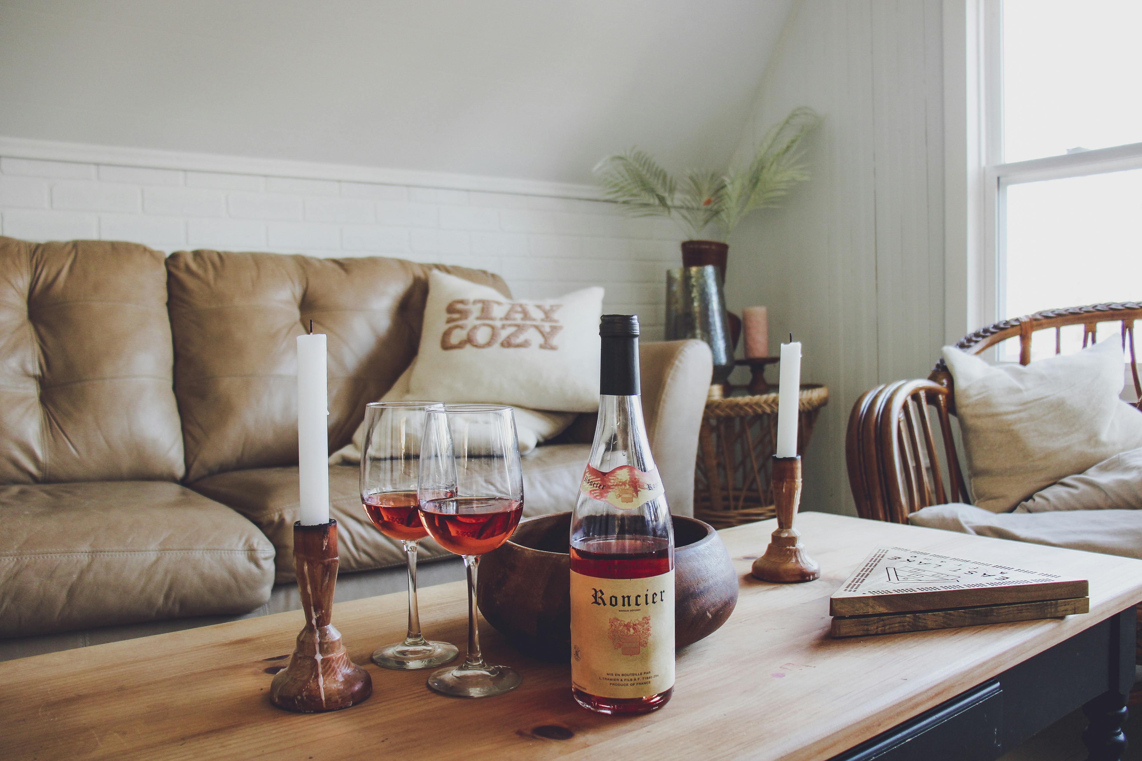 Warm and cozy living room setup with wine, candles, and a comfortable couch.