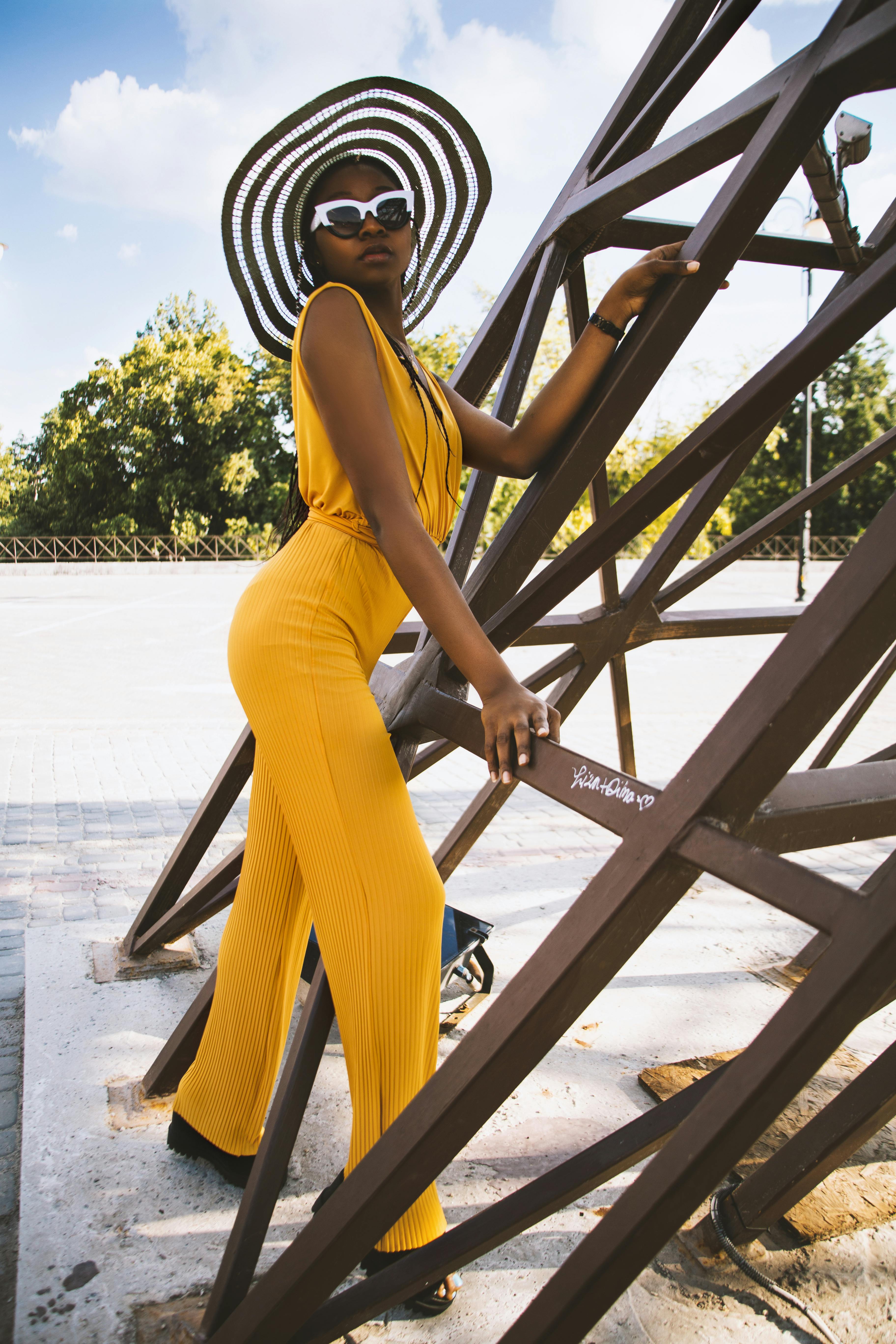 woman wearing yellow overalls holding brown metal frame