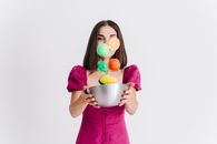 Woman in Purple Long Sleeve Shirt Holding White Ceramic Bowl With Candies