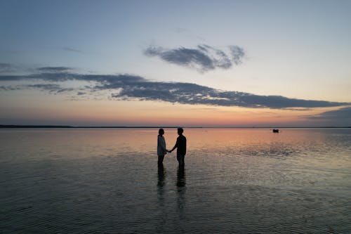 Free Silhouette of Couple Standing on Beach during Sunset Stock Photo