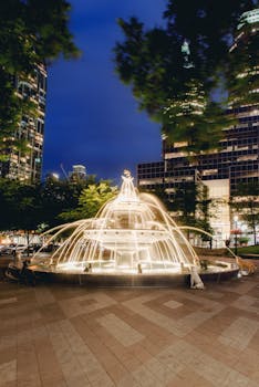 Discover the illuminated Berczy Park Dog Fountain in Toronto with skyscrapers as a backdrop.