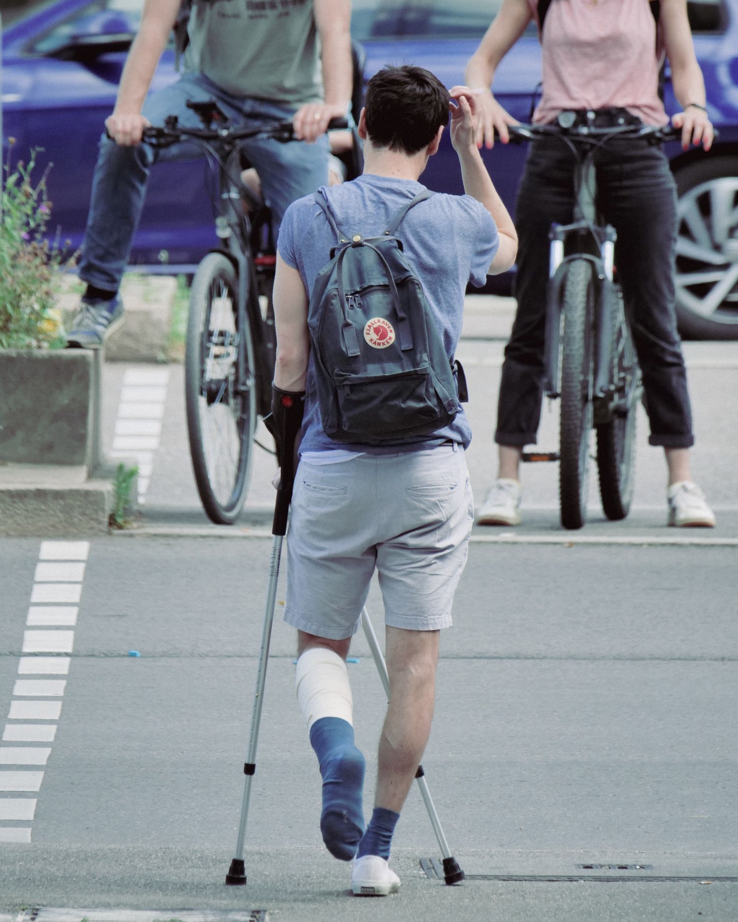 Person with leg injury using crutches on a street