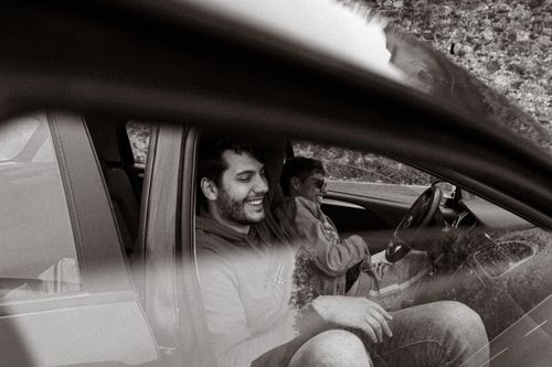Free Two men laughing and enjoying a road trip inside a car, captured in black and white photograph. Stock Photo