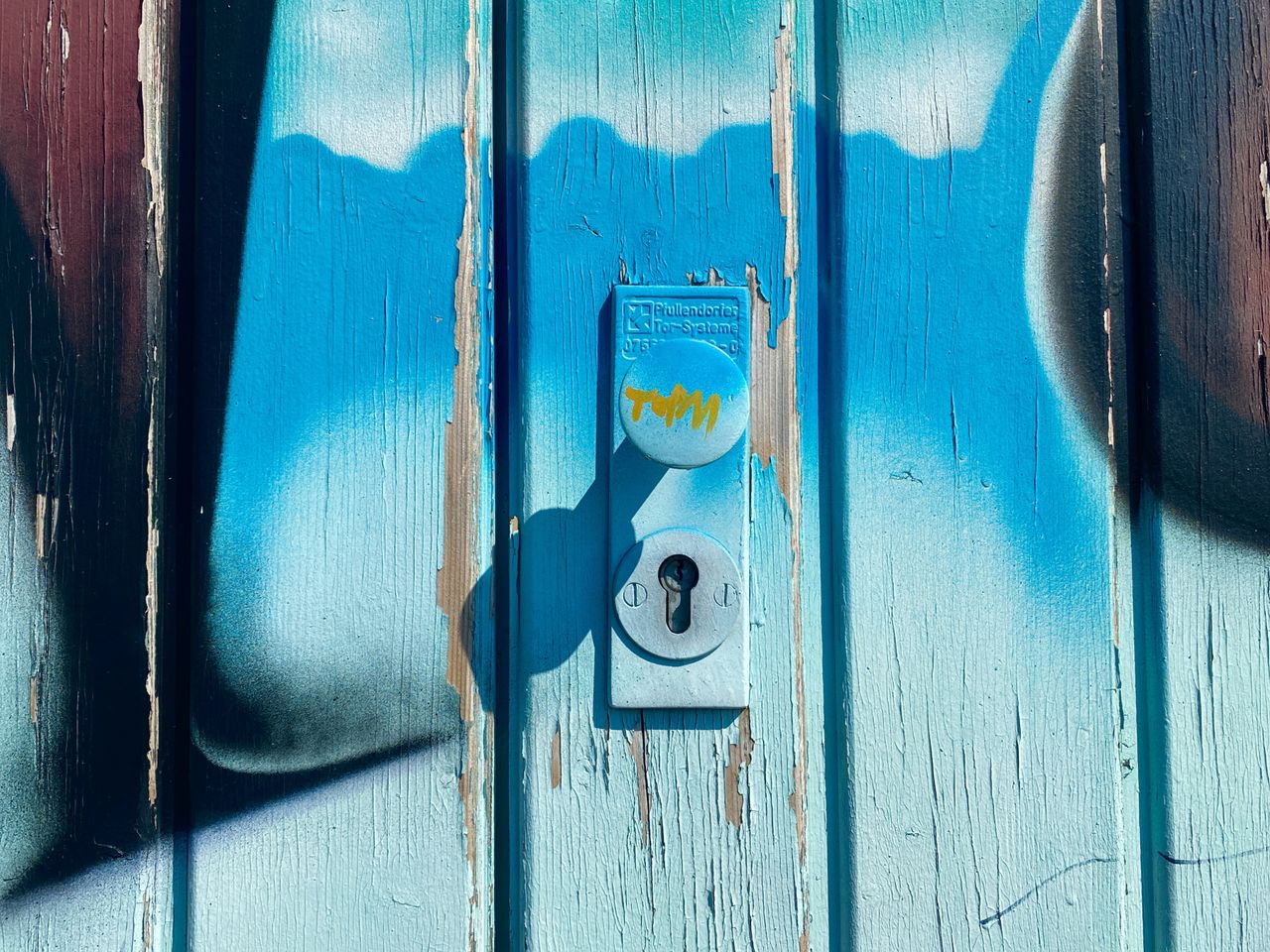 close up of a vibrant wooden door with graffiti art surrounding a keyh