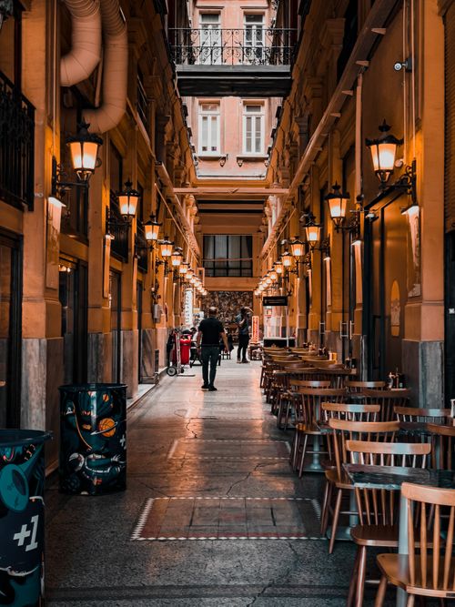 Free Explore a charming alley in Istanbul with street cafes, wooden chairs, and vintage lighting. Stock Photo