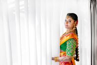 Woman in Red and Yellow Floral Dress Standing Beside White Curtain