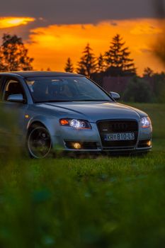Stunning Audi car parked in a grassy field during a vibrant sunset, capturing luxury and nature.