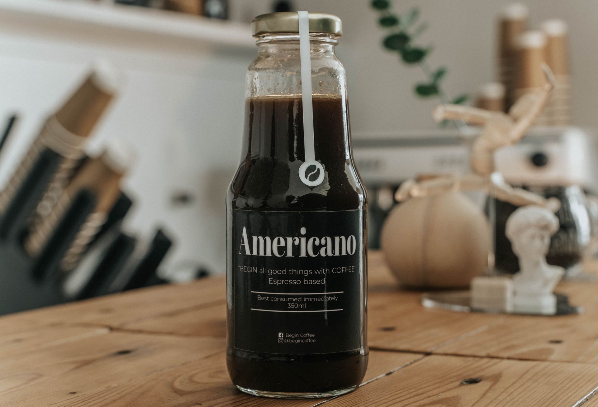 Close-up of Americano coffee in a glass bottle on a wooden table with soft lighting.