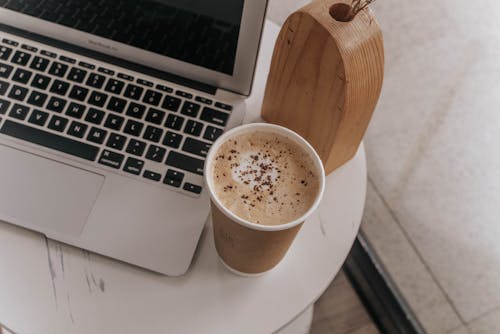 Close-Up Shot of a Cup of Coffee near a Laptop