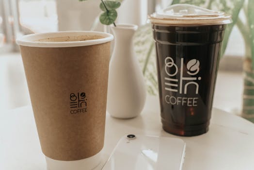 A close-up of two coffee cups on a white table with minimalist decor.