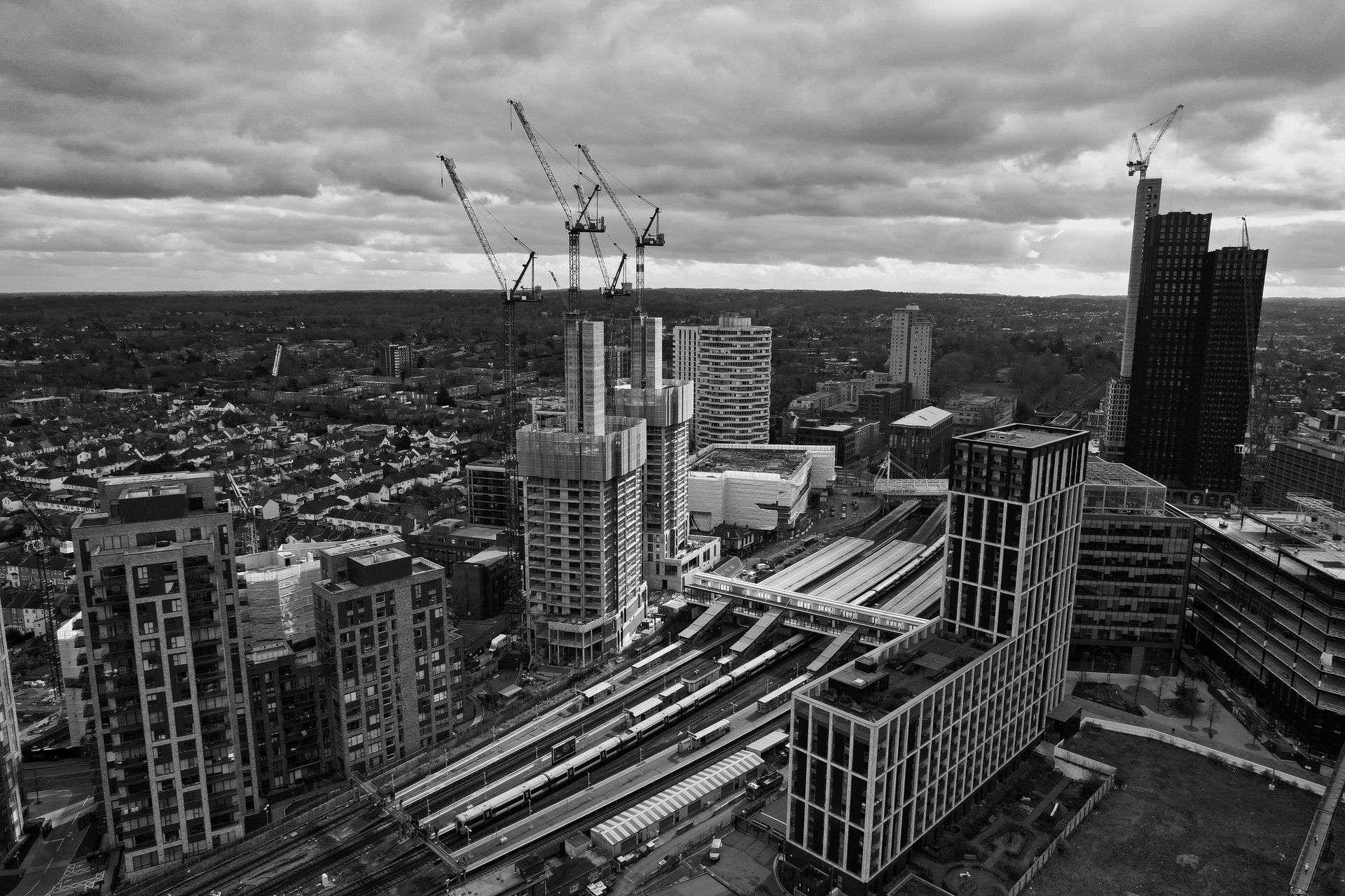 Black and white aerial view of urban construction in Greater London with cranes and buildings.