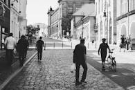 一个人走在古老小镇的鹅卵石街道上，背景是黑白照片中的建筑