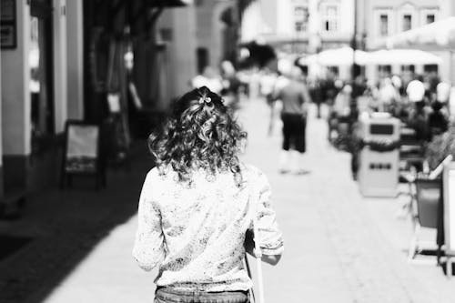 Grayscale Photo on Woman Walks on Sidewalk