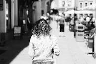 一位卷发女子走在繁华的都市街头，画面以高对比度的黑白风格拍摄