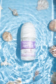 Beauty product in water surrounded by seashells, perfect for skincare promotion.