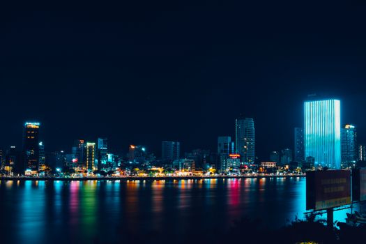 Stunning night view of Da Nang's illuminated skyline reflecting over the water.
