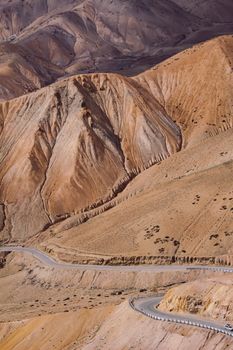 A stunning view of a barren mountain range with a winding road below, showcasing natural erosion.