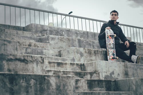 Man Holding Skateboard Sitting On Stairs