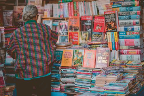 Free A senior woman in colorful attire browsing a diverse book display in a bookstore. Stock Photo